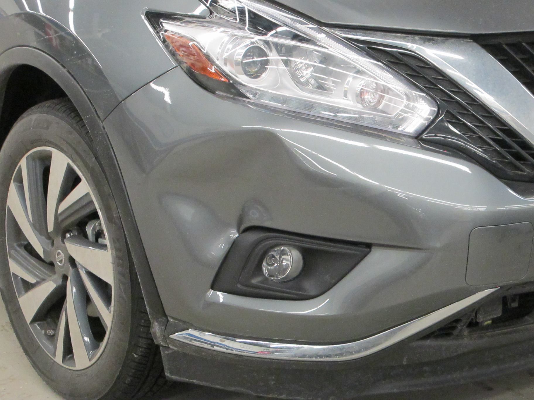 A close up of a nissan murano with a damaged bumper.