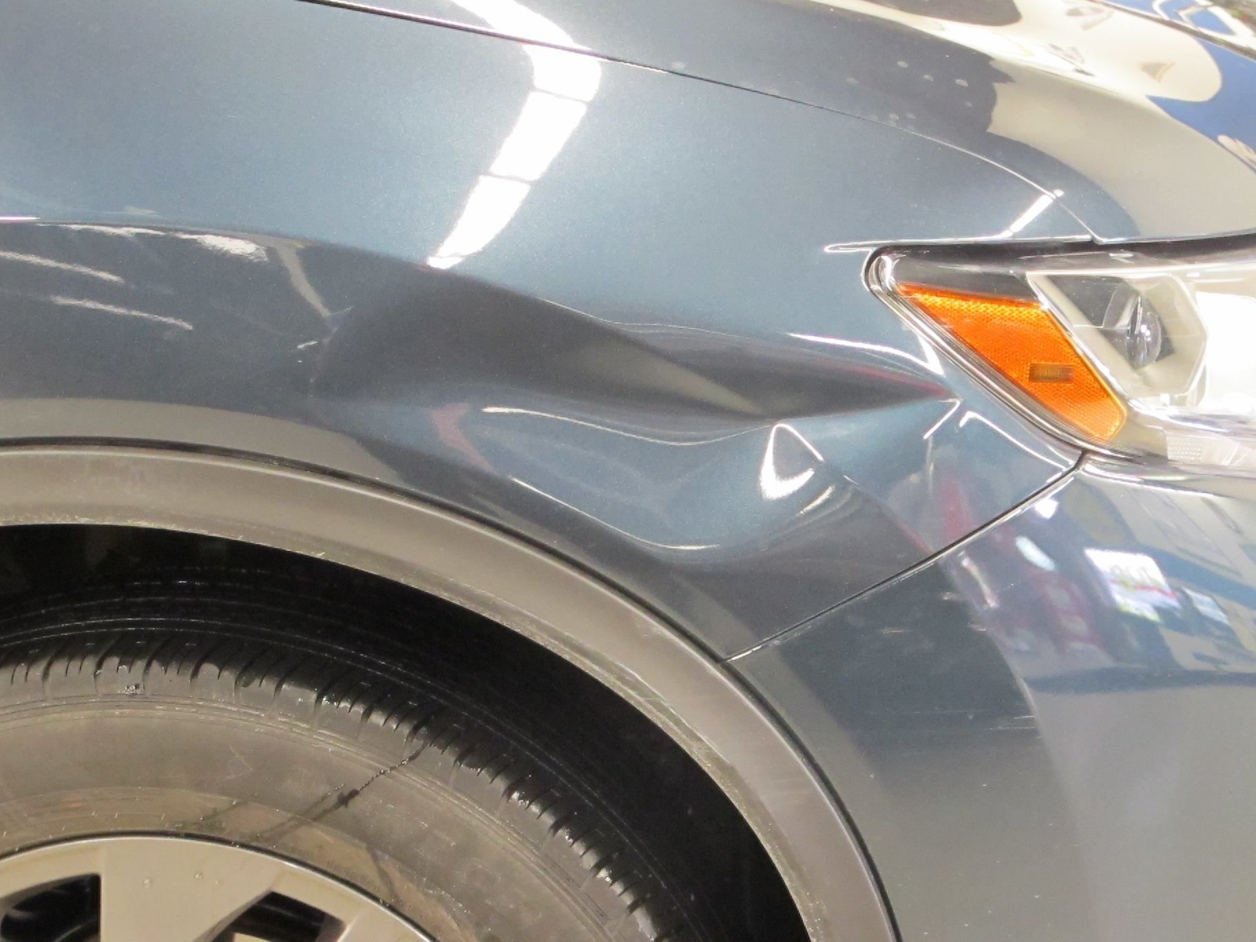 A close up of a car with a damaged fender