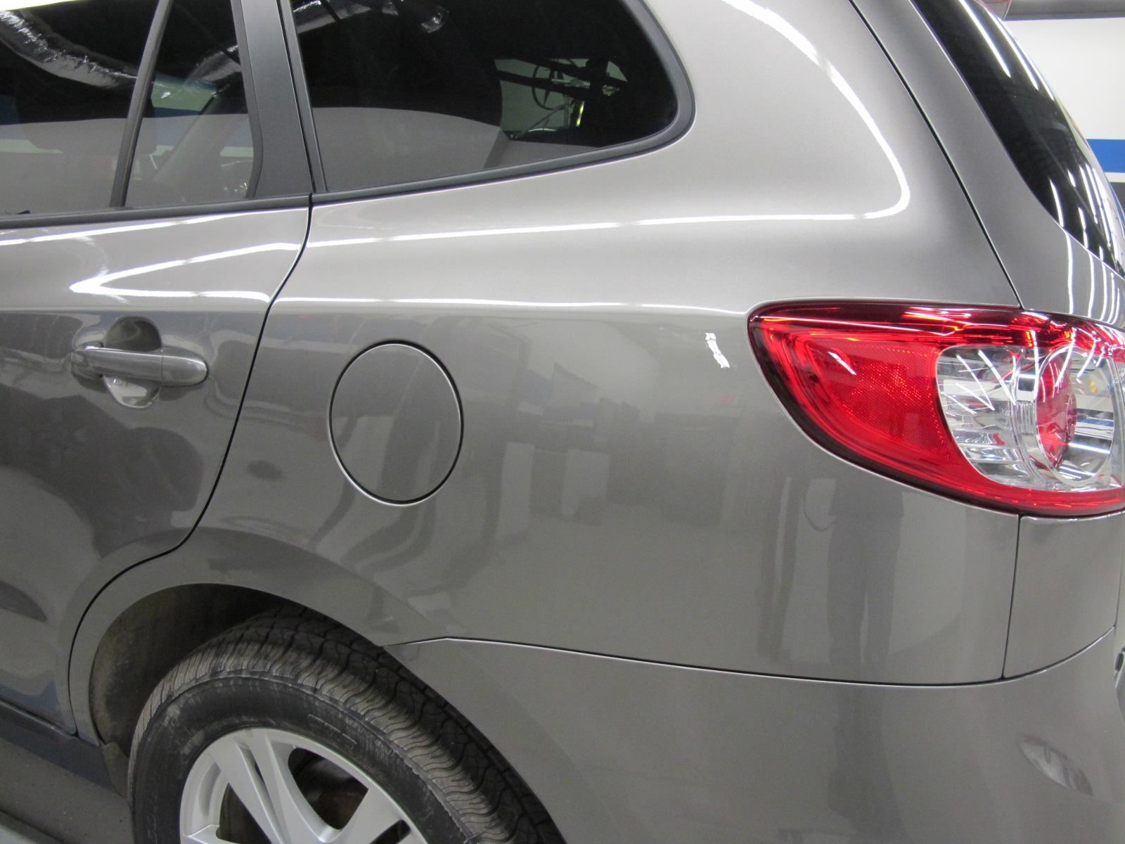 A gray car with a red tail light is parked in a garage