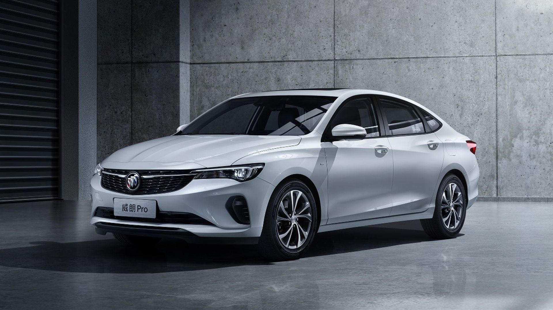 A white car is parked in a garage next to a concrete wall.