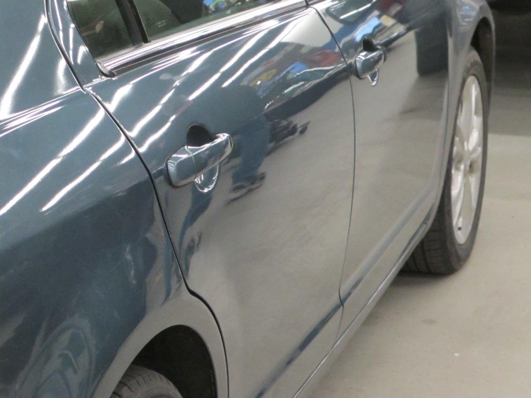 A blue car is parked in a garage with the door open