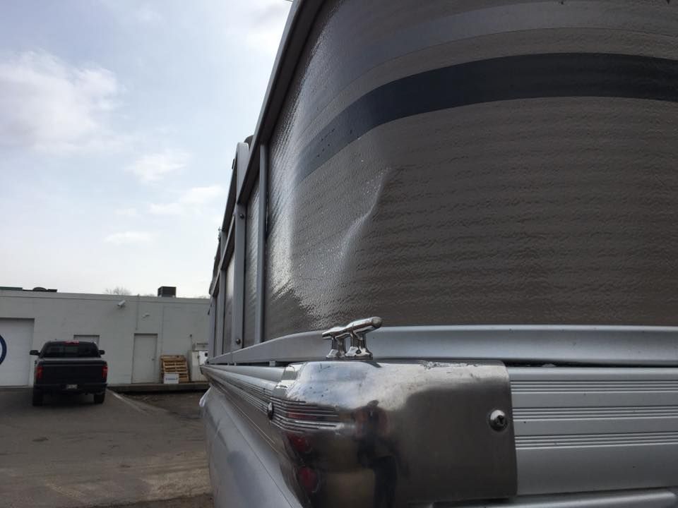 A boat is parked in a parking lot next to a truck.