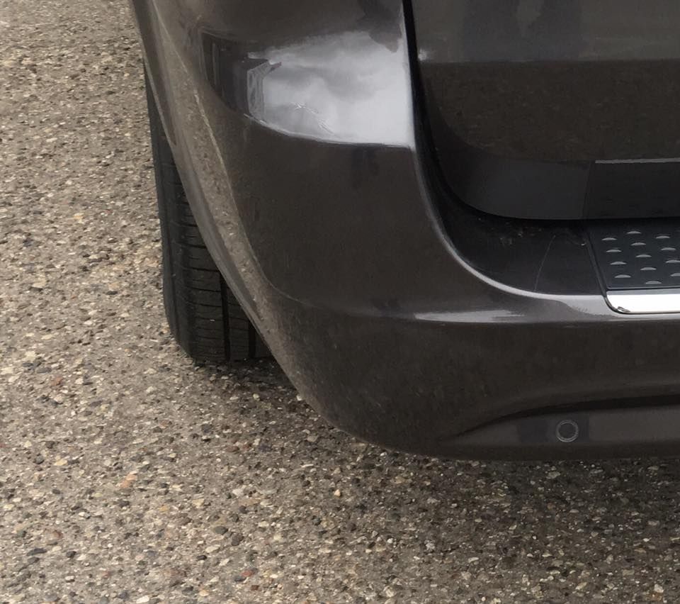 A gray car is parked on a gravel road