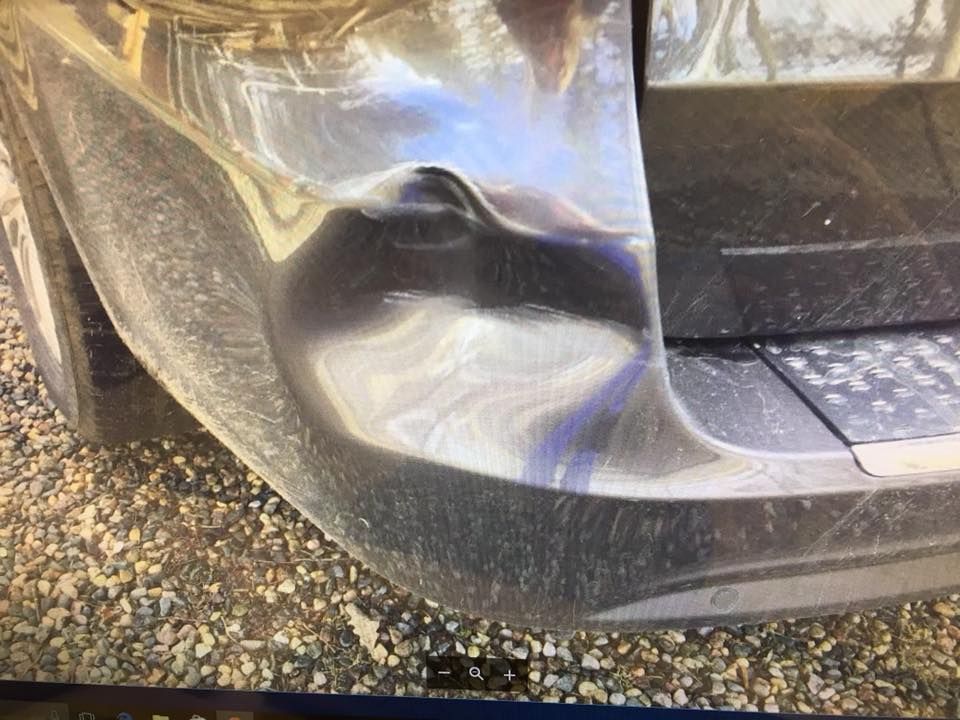 A close up of a car 's bumper on a gravel road.