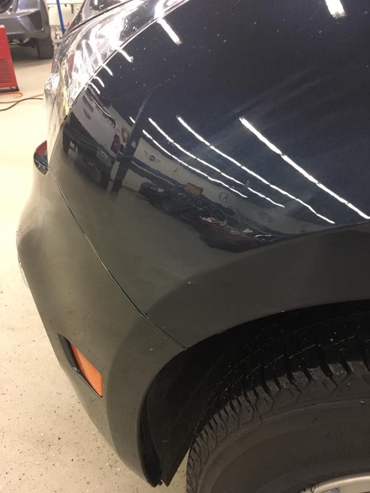 A close up of a black car 's bumper in a garage