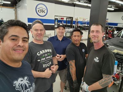 A group of men are posing for a picture in a garage.