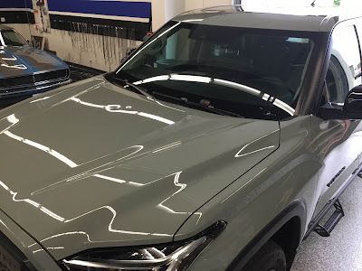 A gray suv is parked in a garage next to a black suv.