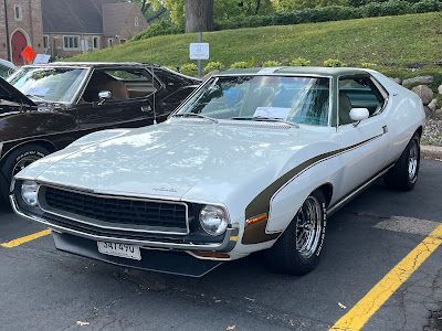 A white car is parked in a parking lot next to another car.