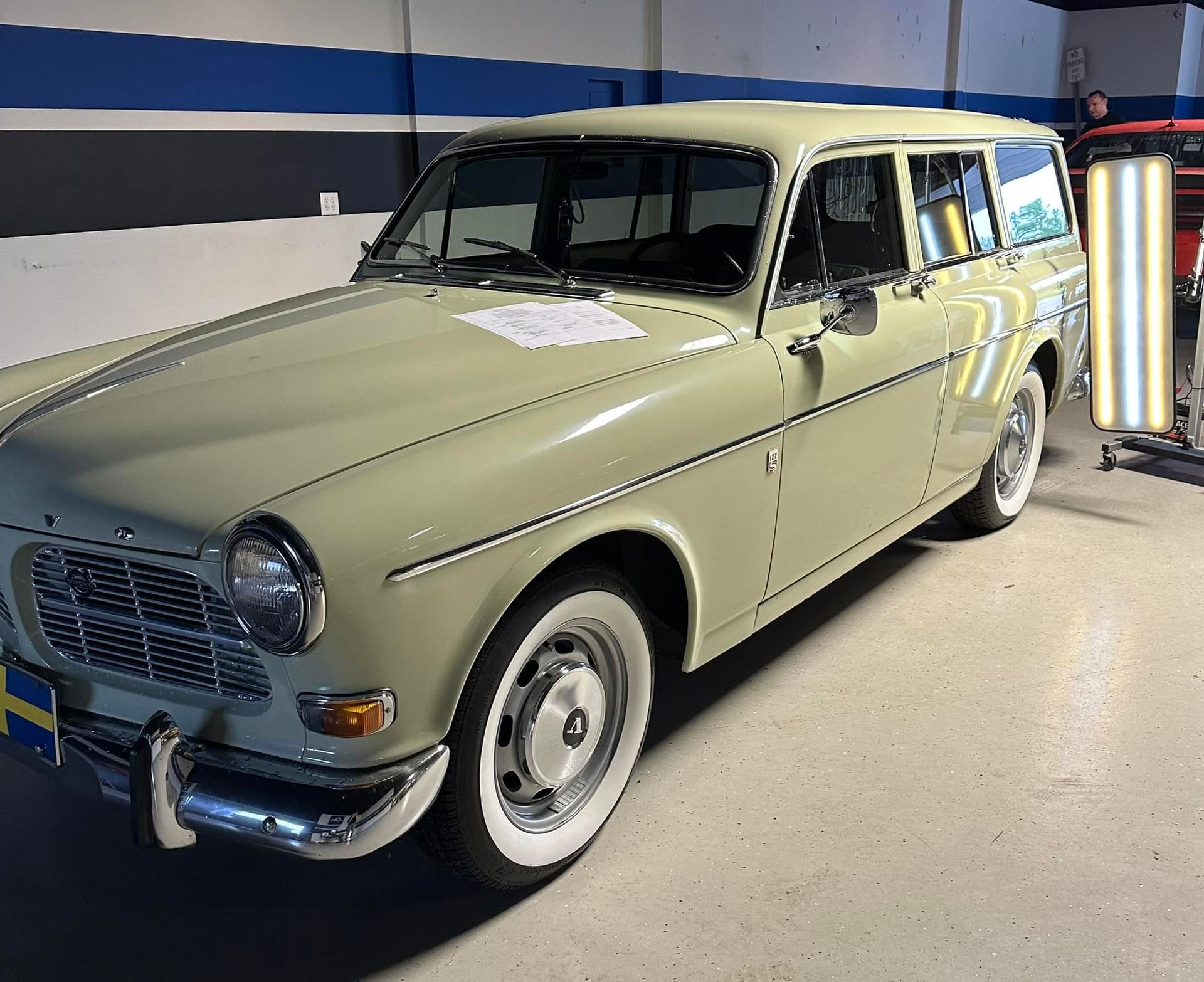 A green car with white tires is parked in a garage