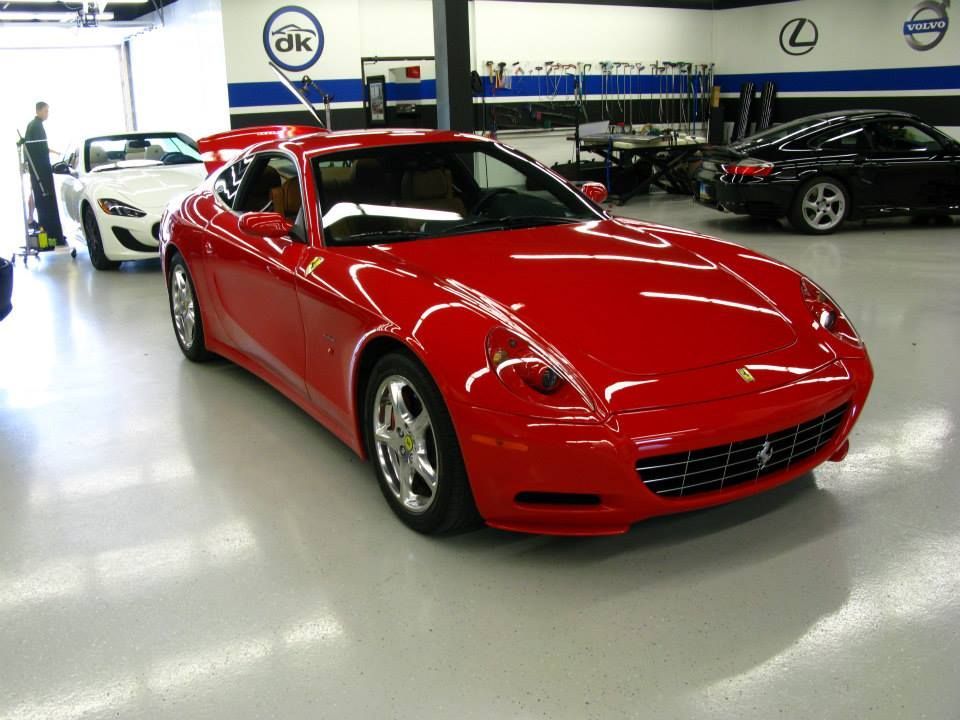 A red ferrari is parked in a garage with other cars