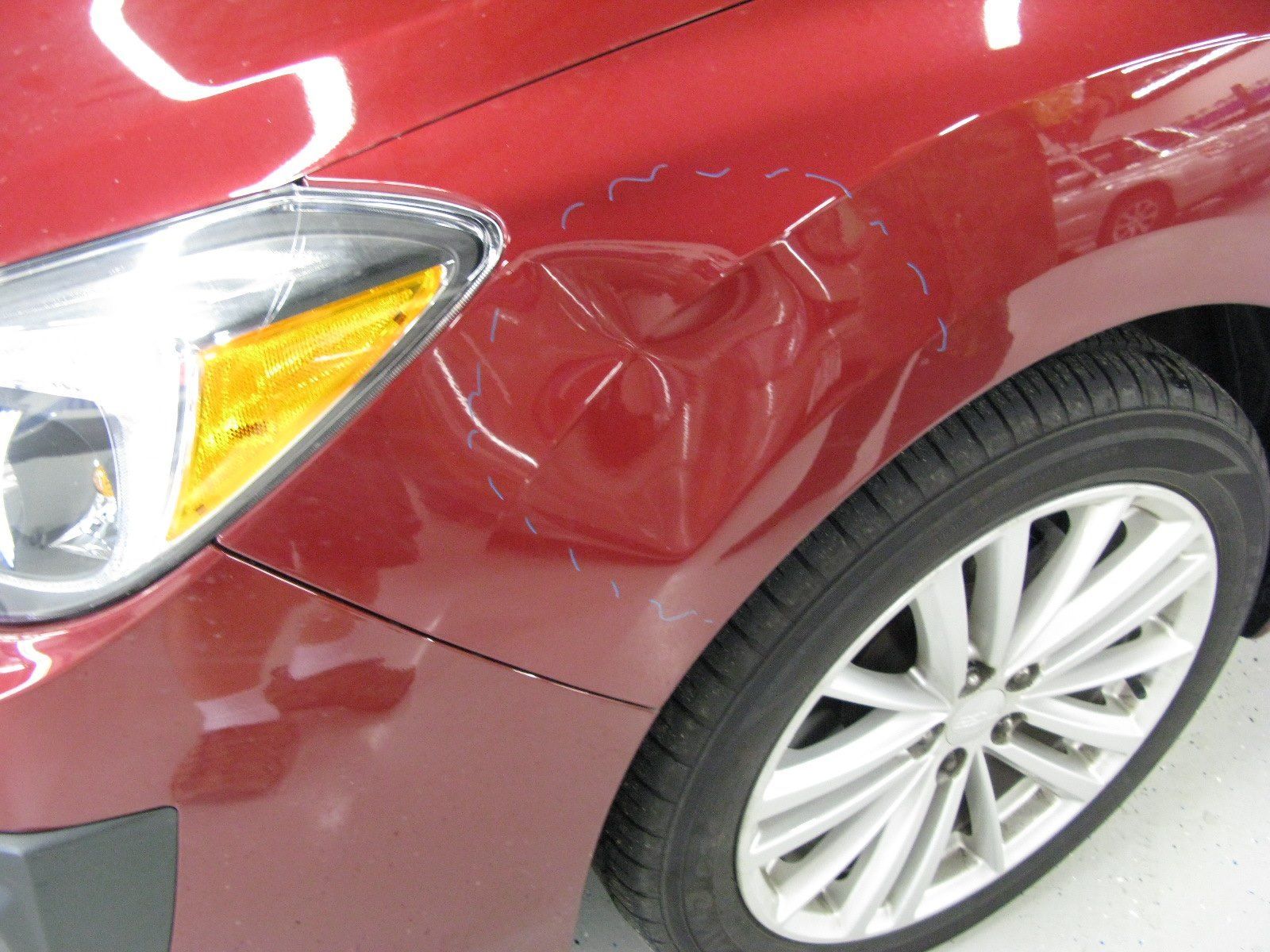 A close up of a red car with a damaged fender