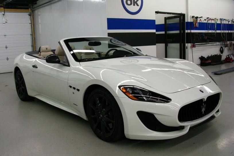 A white maserati convertible is parked in a garage.