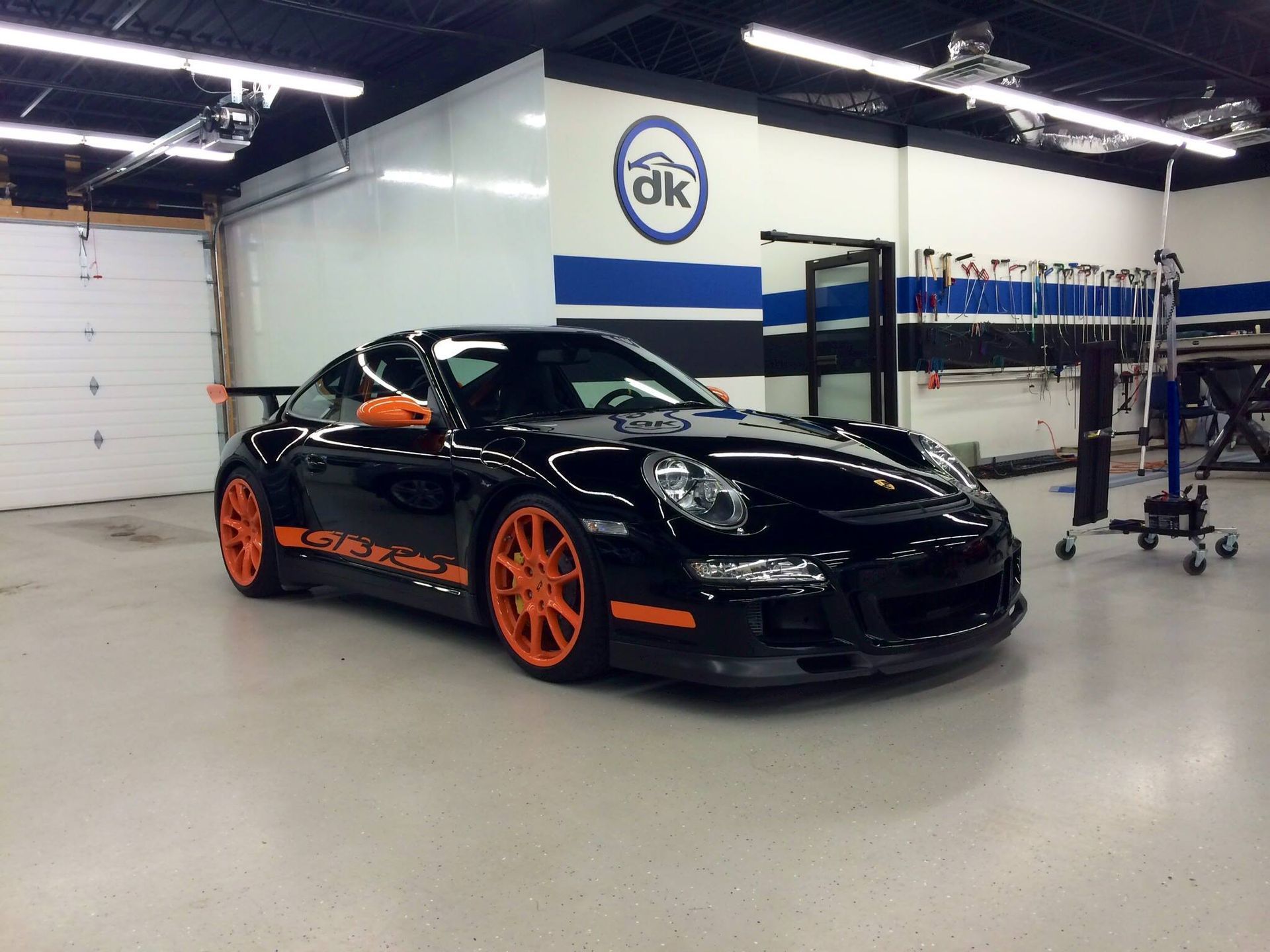 A black porsche with orange wheels is parked in a garage