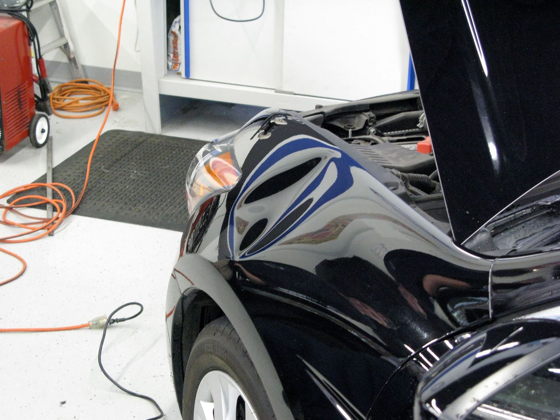 A black car with the hood open in a garage