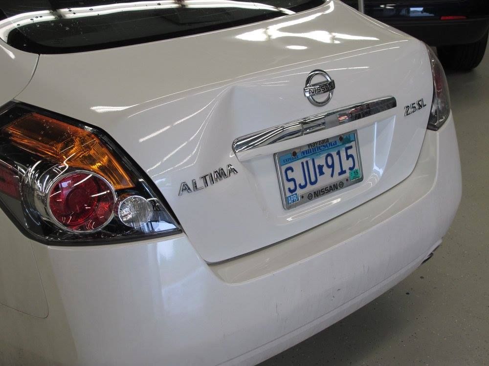 A white nissan altima with a blue license plate