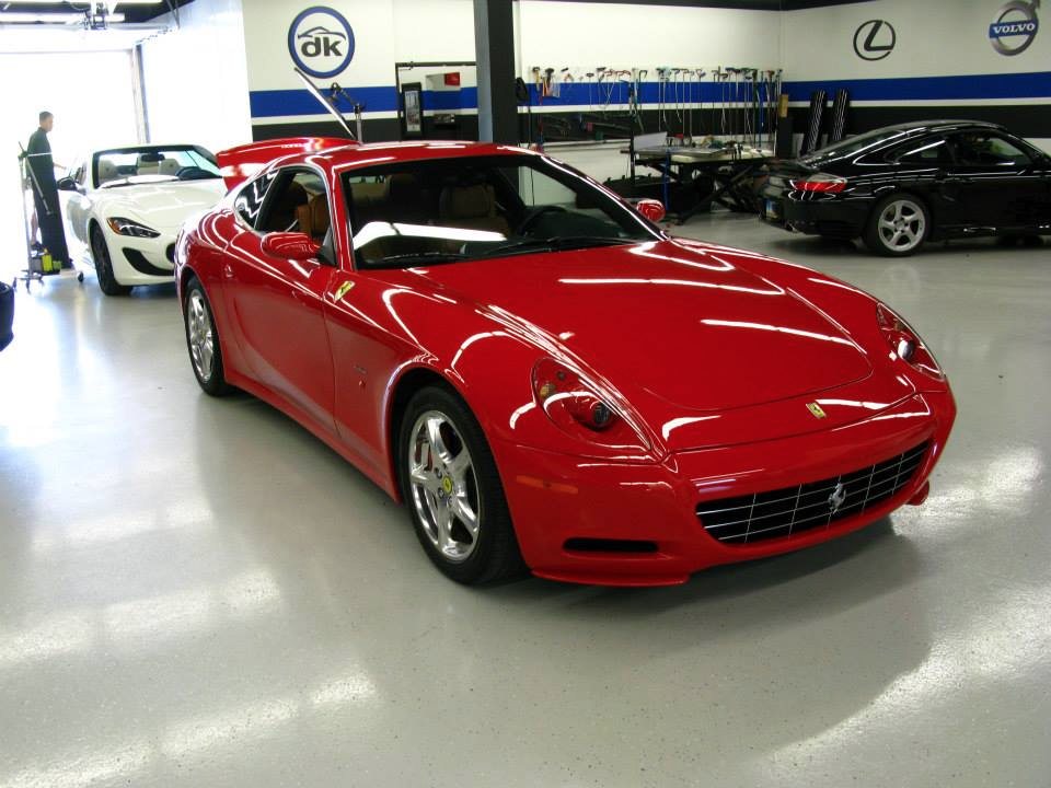 A red ferrari is parked in a garage with other cars