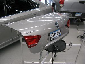 The trunk of a volkswagen passat is sitting on a stand in a garage.