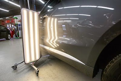 A car is being painted in a garage with a light on it.