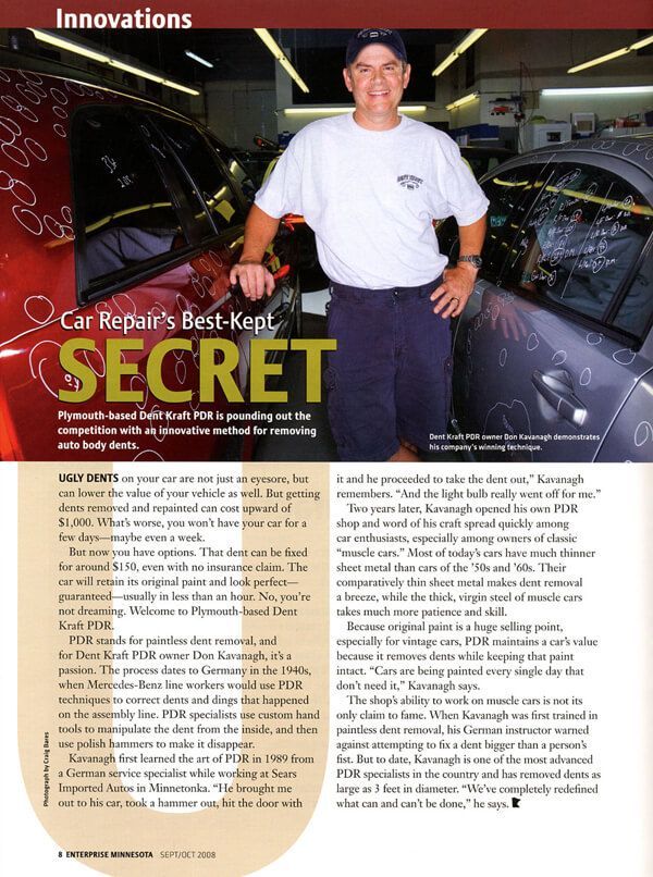A man is standing in front of a car in a car repair shop.