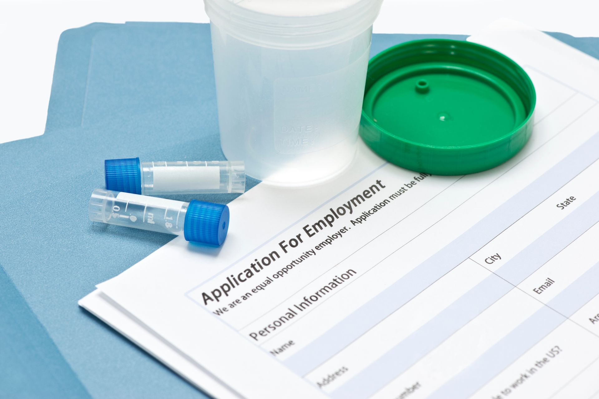 A job application surrounded by drug testing materials and blue folders.