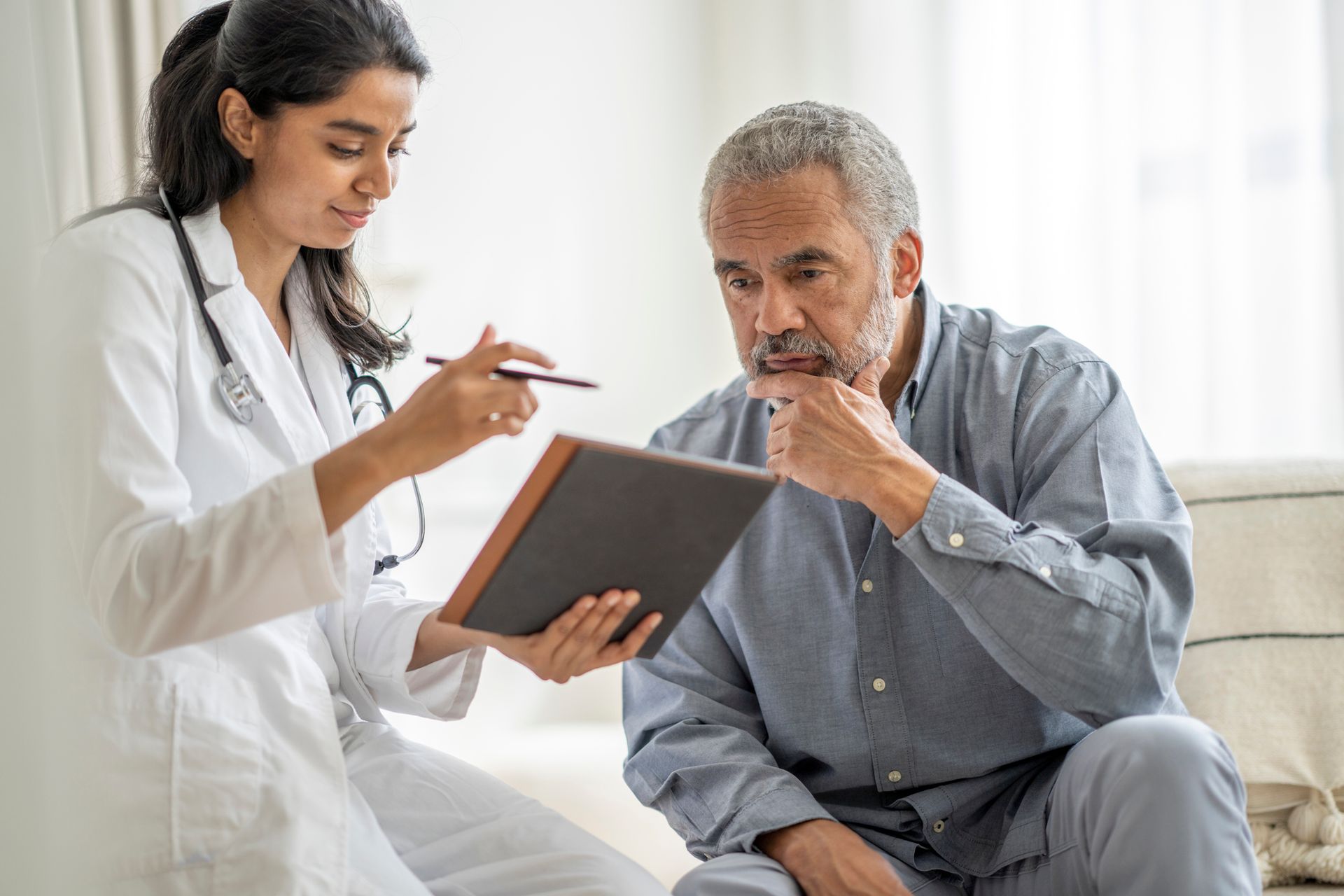 Man visiting doctor, reading his medical test results with a focused expression. Man visiting doctor, reading his medical test results with a focused expression.