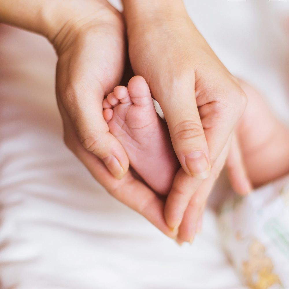 A Woman is Holding a Baby's Foot in Her Hands — Life24 Health Bowen Therapy In Lavington, NSW