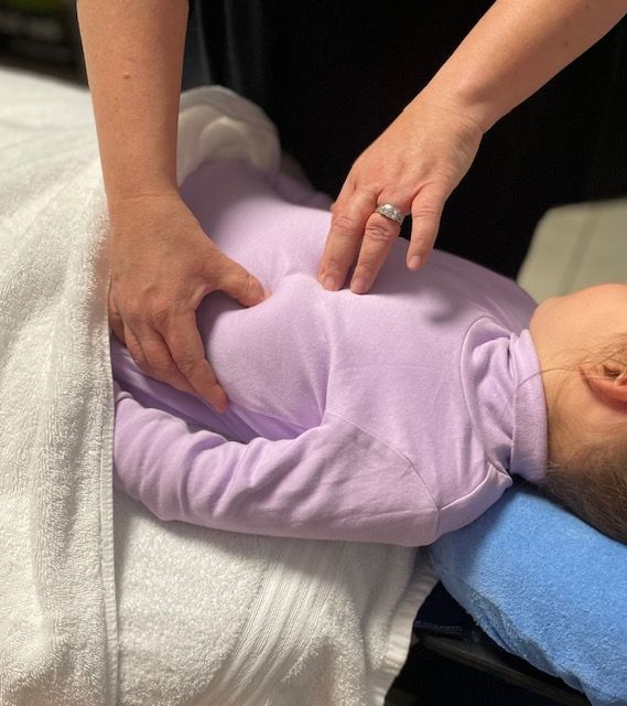 A Baby In A Purple Shirt Is Getting A Massage — Life24 Health Bowen Therapy In Lavington, NSW