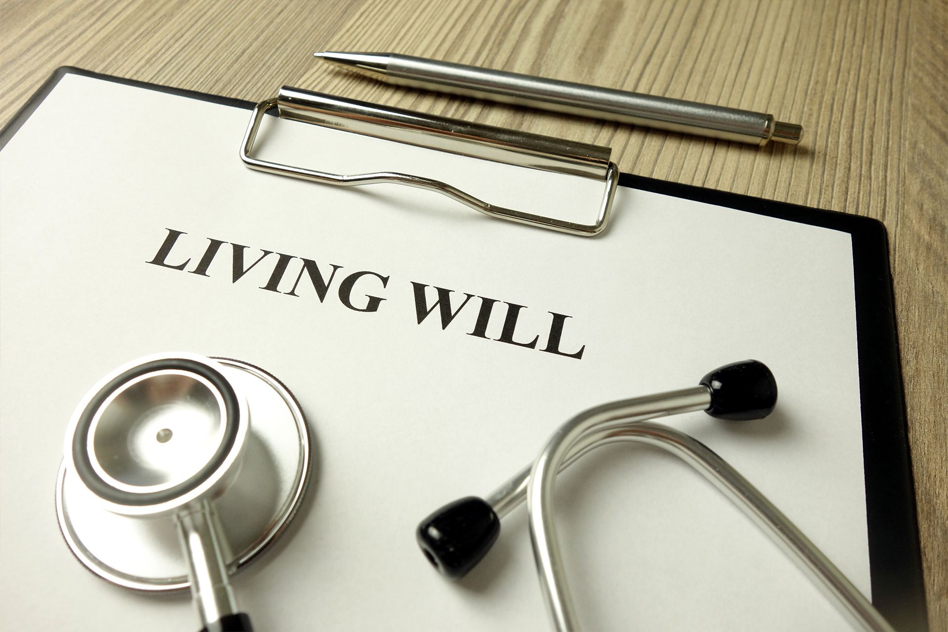 Living will on a clipboard with a stethoscope and pen, on a wooden surface.