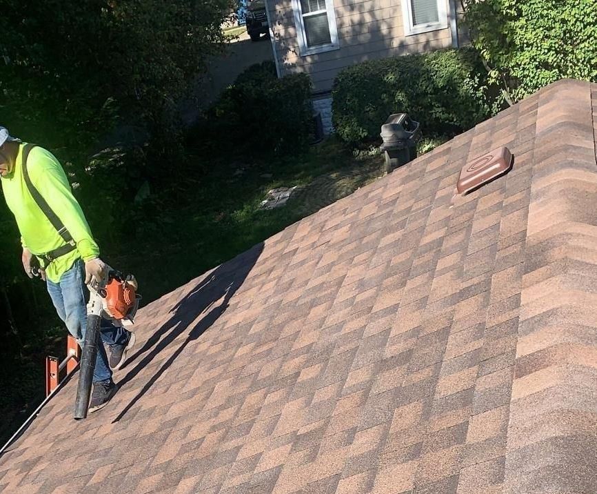 A man is standing on top of a roof with a vacuum cleaner.