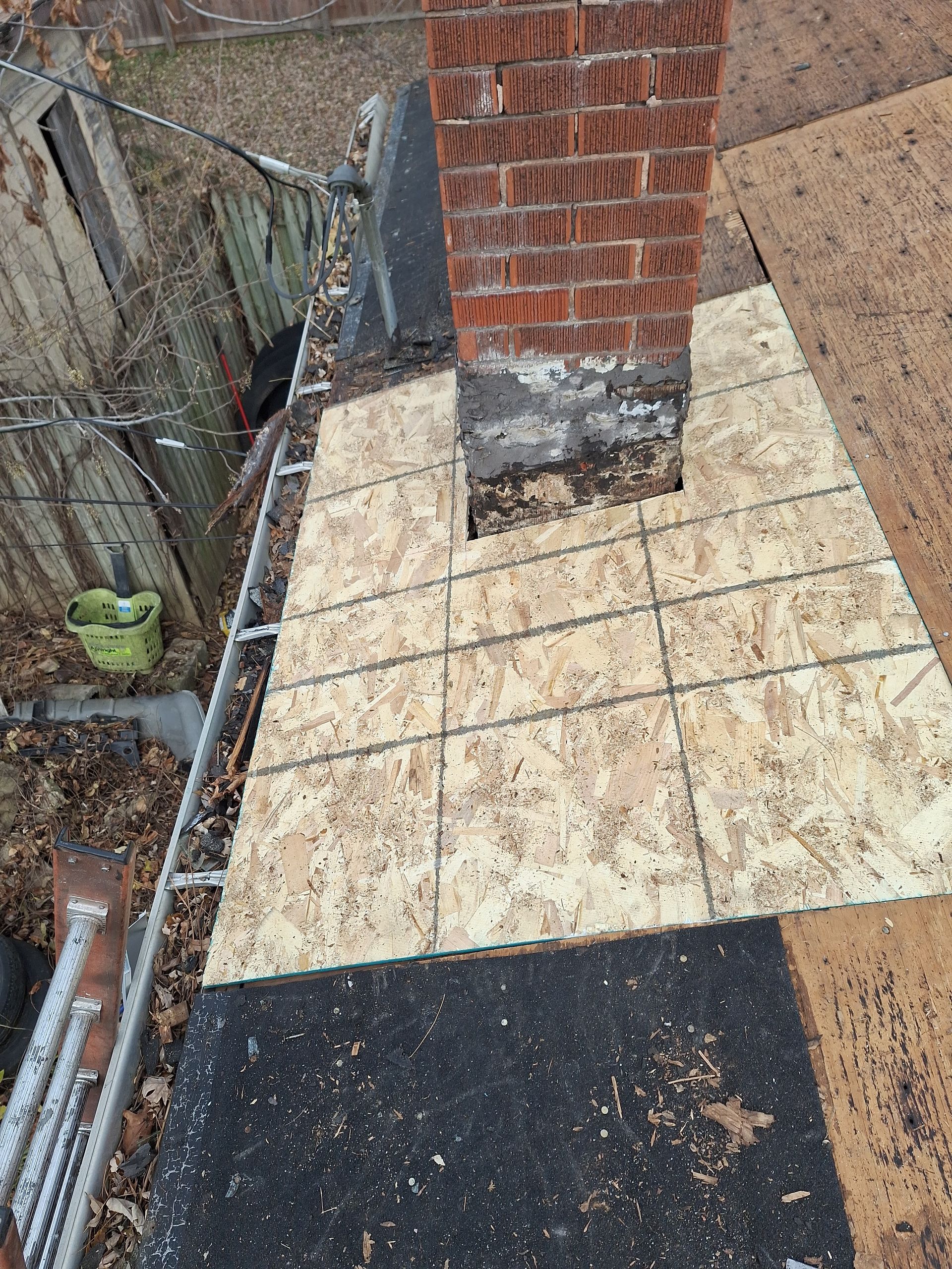 A brick chimney is sitting on top of a tiled roof.