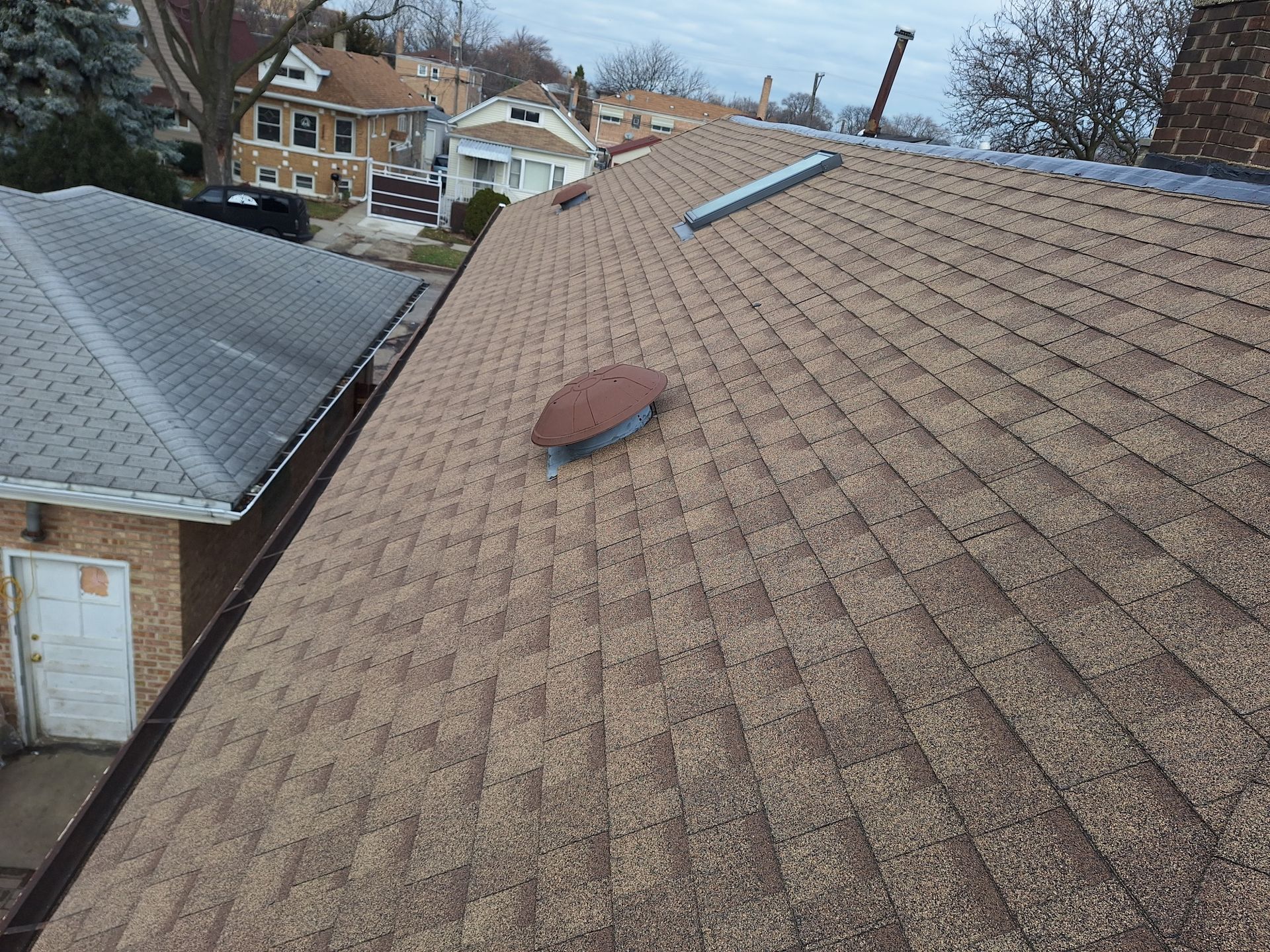 The roof of a house has a vent on it.