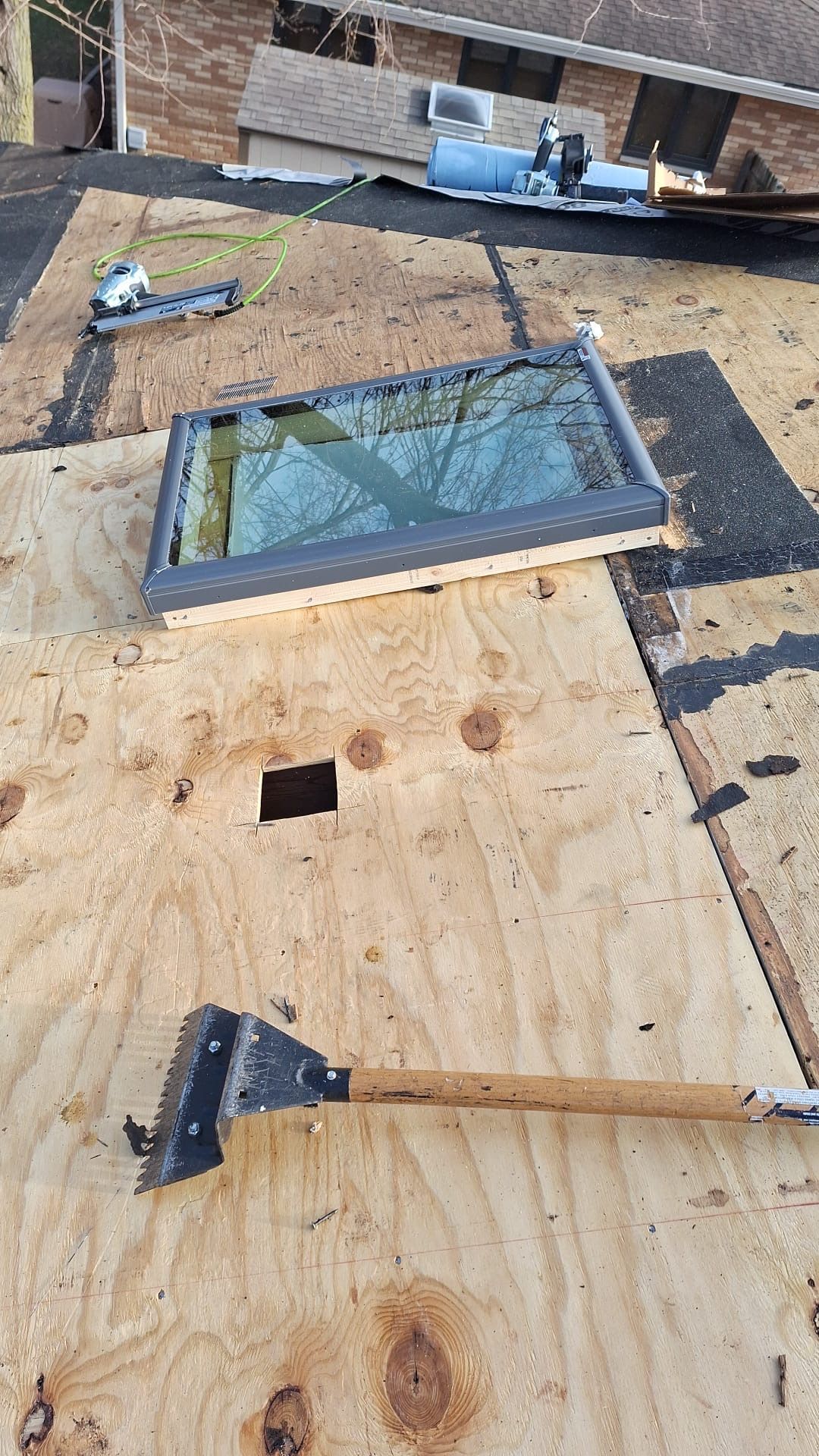 A roof with a skylight and a hammer on it.