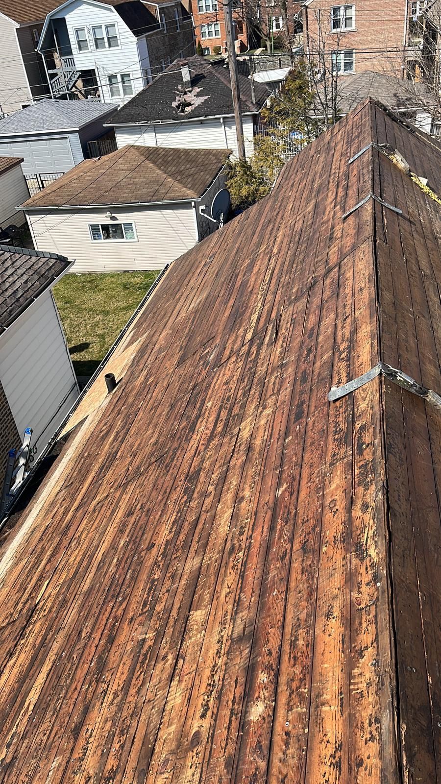 A close up of a wooden roof with a few houses in the background.