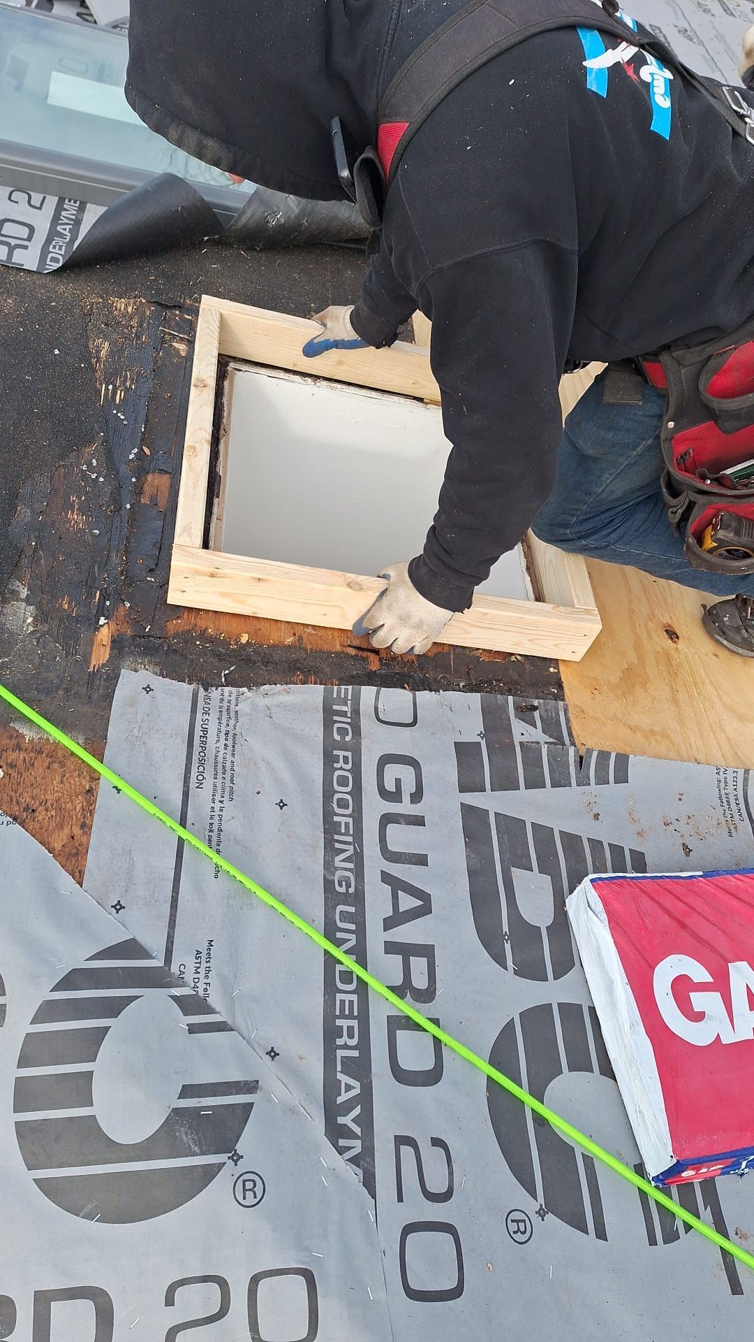 A man is installing a skylight on a roof.