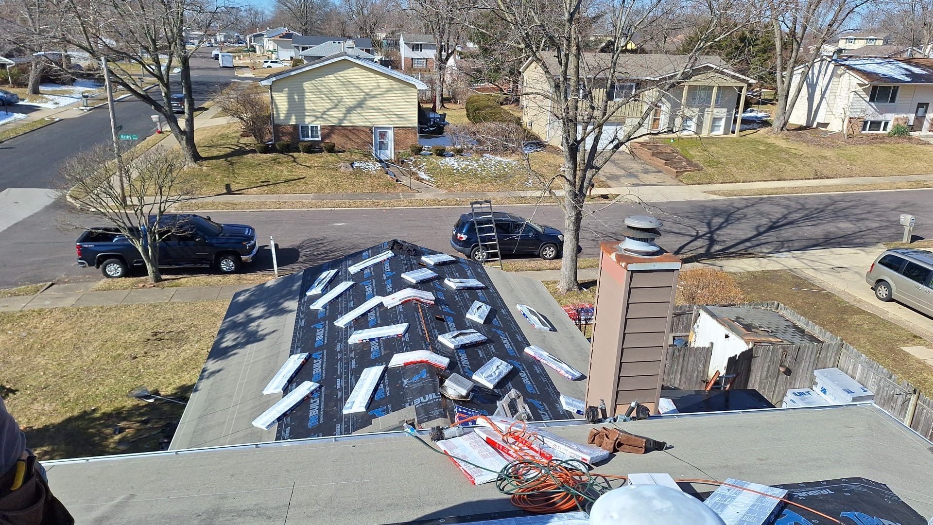 An aerial view of a roof being repaired in a residential area.