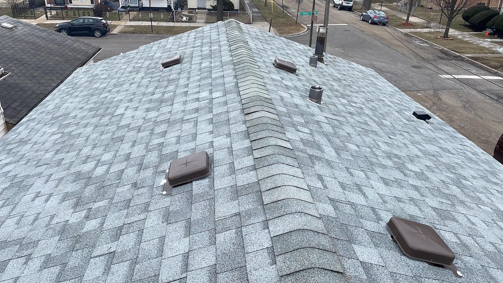 A roof with a lot of shingles on it and a street in the background.