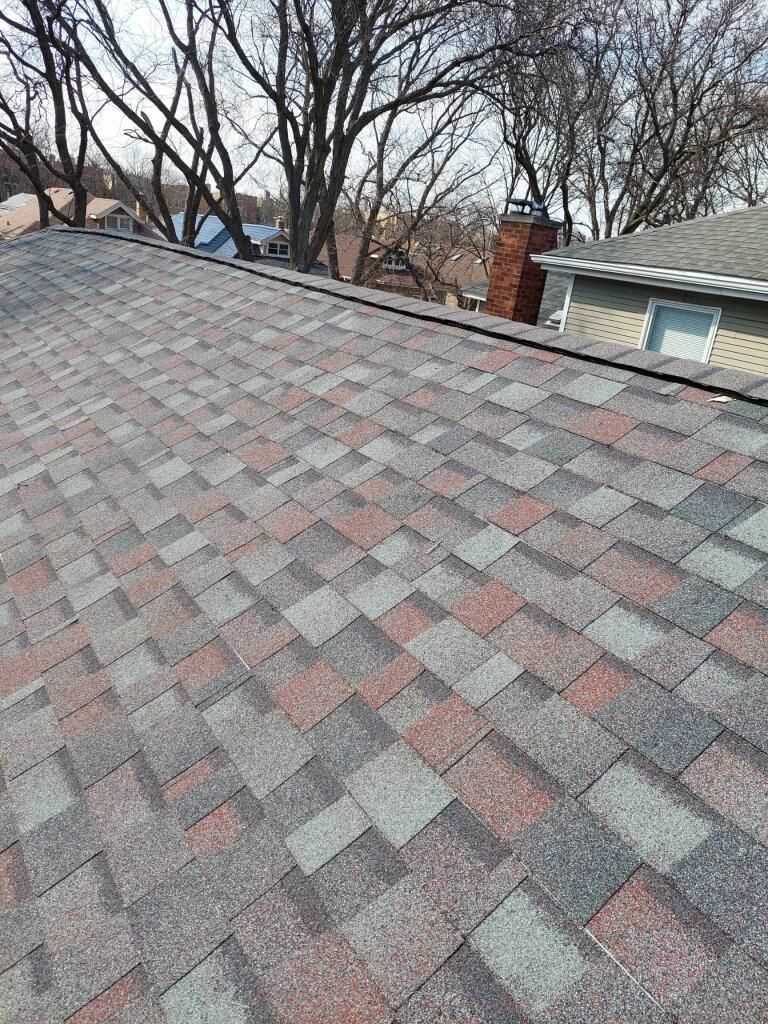 A close up of a roof with a chimney and trees in the background.