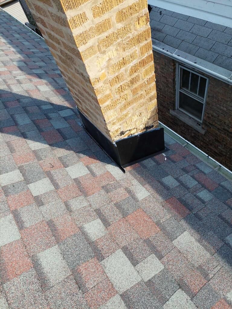 A chimney is sitting on top of a roof next to a house.