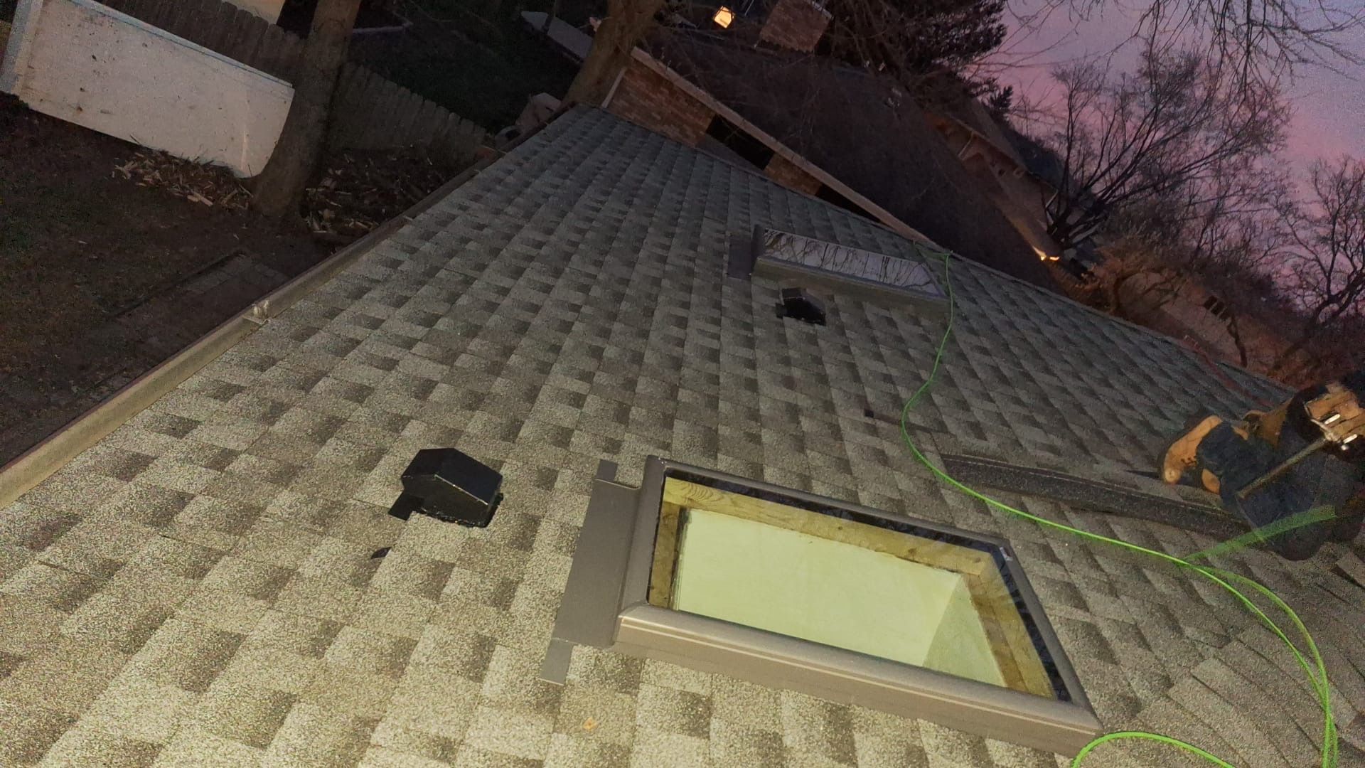 A person is standing on top of a roof with a skylight.