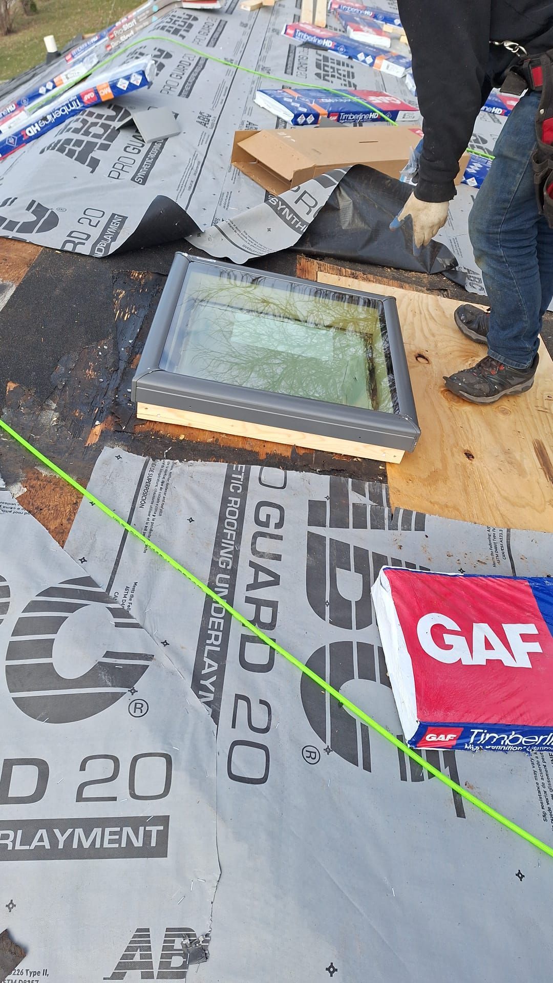 A man is installing a skylight on a roof.