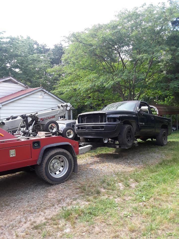 A black truck is being towed by a red tow truck.
