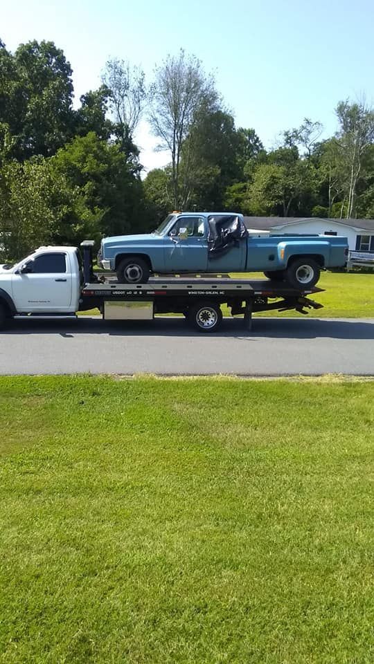 A blue truck is being towed by a tow truck.