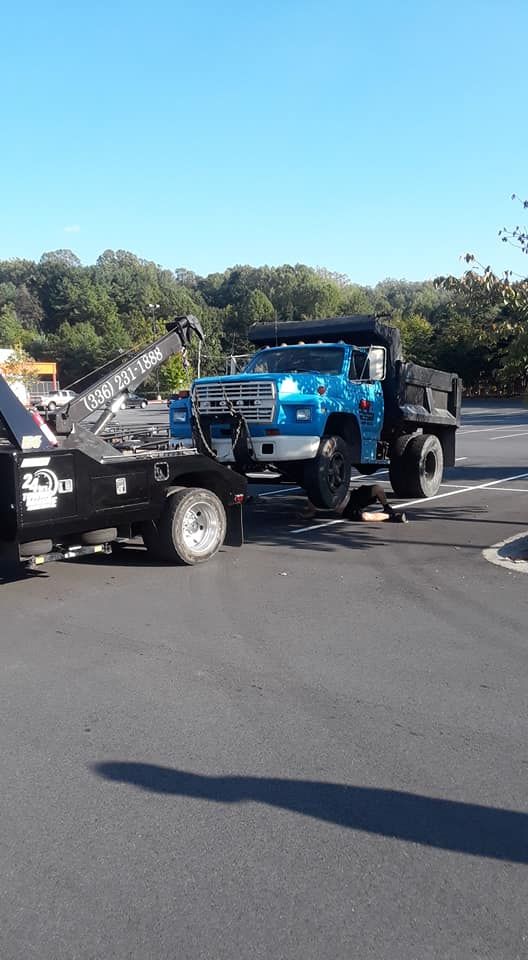 A blue truck is being towed by a black tow truck.