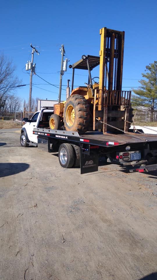 A forklift is being towed by a tow truck.