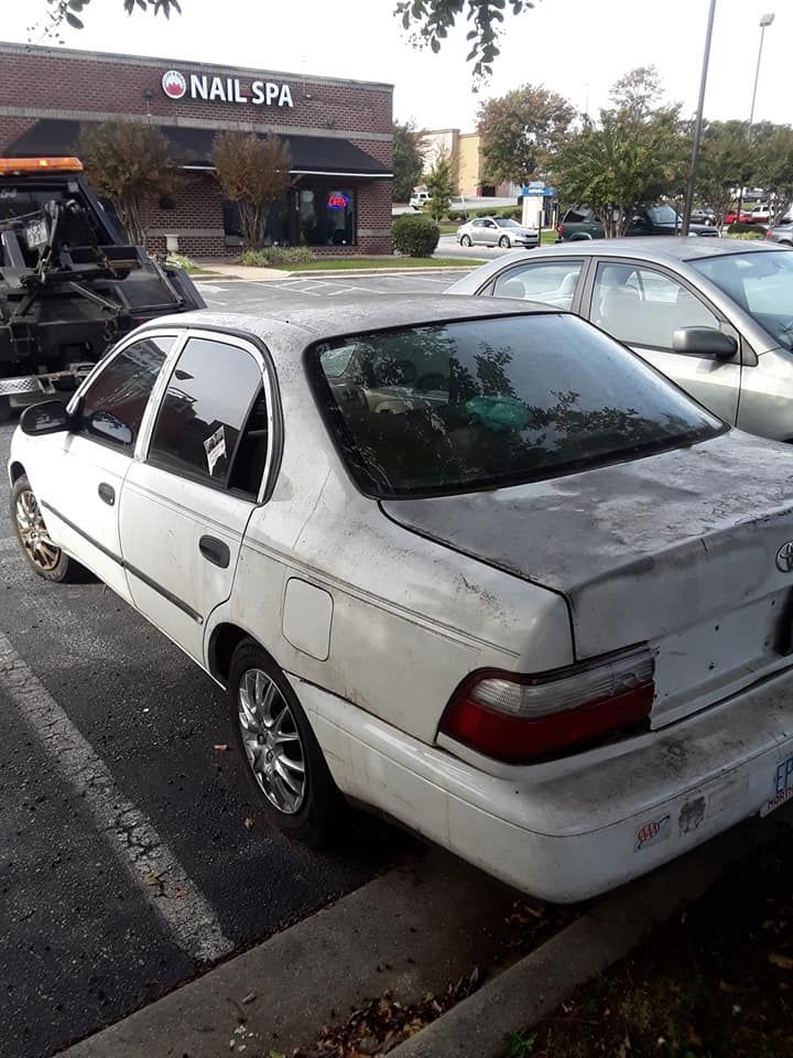A white car is parked in front of a nail spa