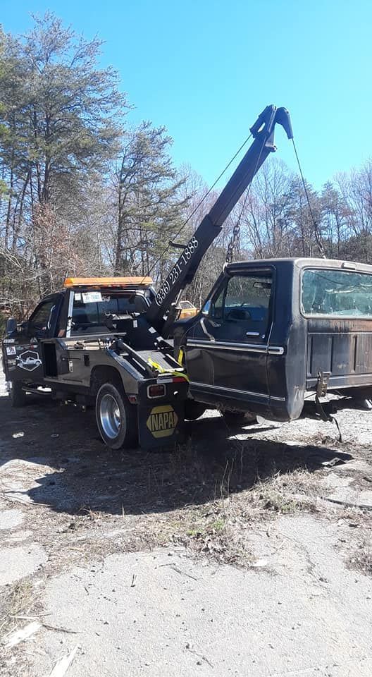 A tow truck is towing a truck in the mud.