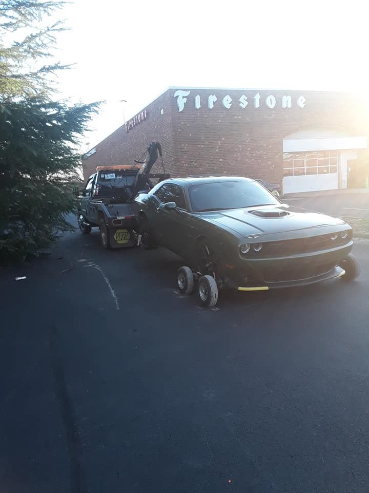 A dodge challenger is being towed by a tow truck.