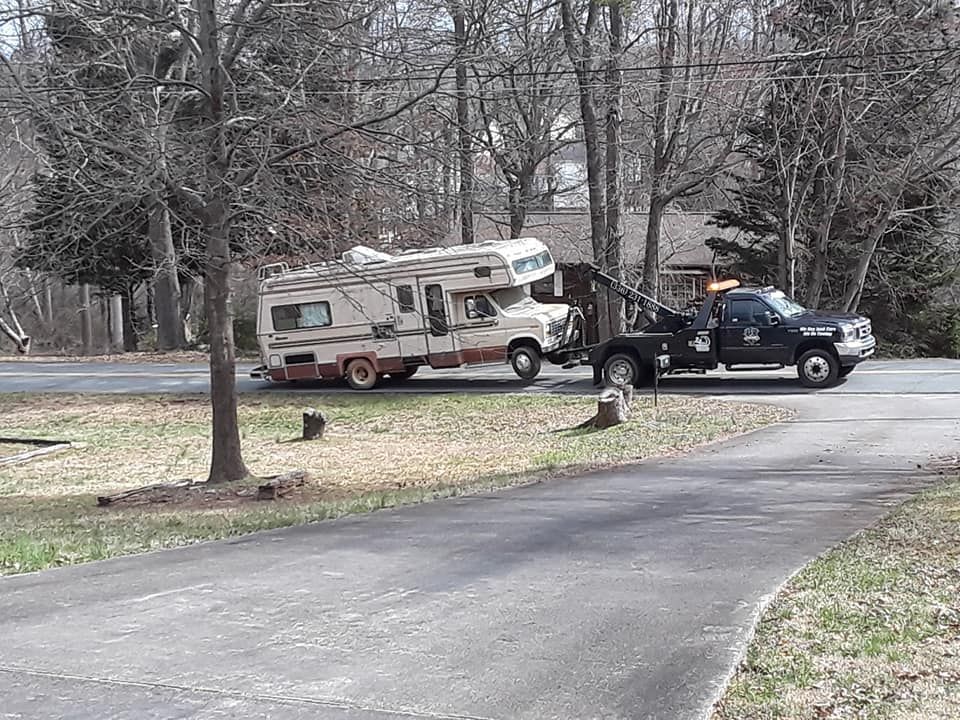 A rv is being towed down a road by a tow truck.