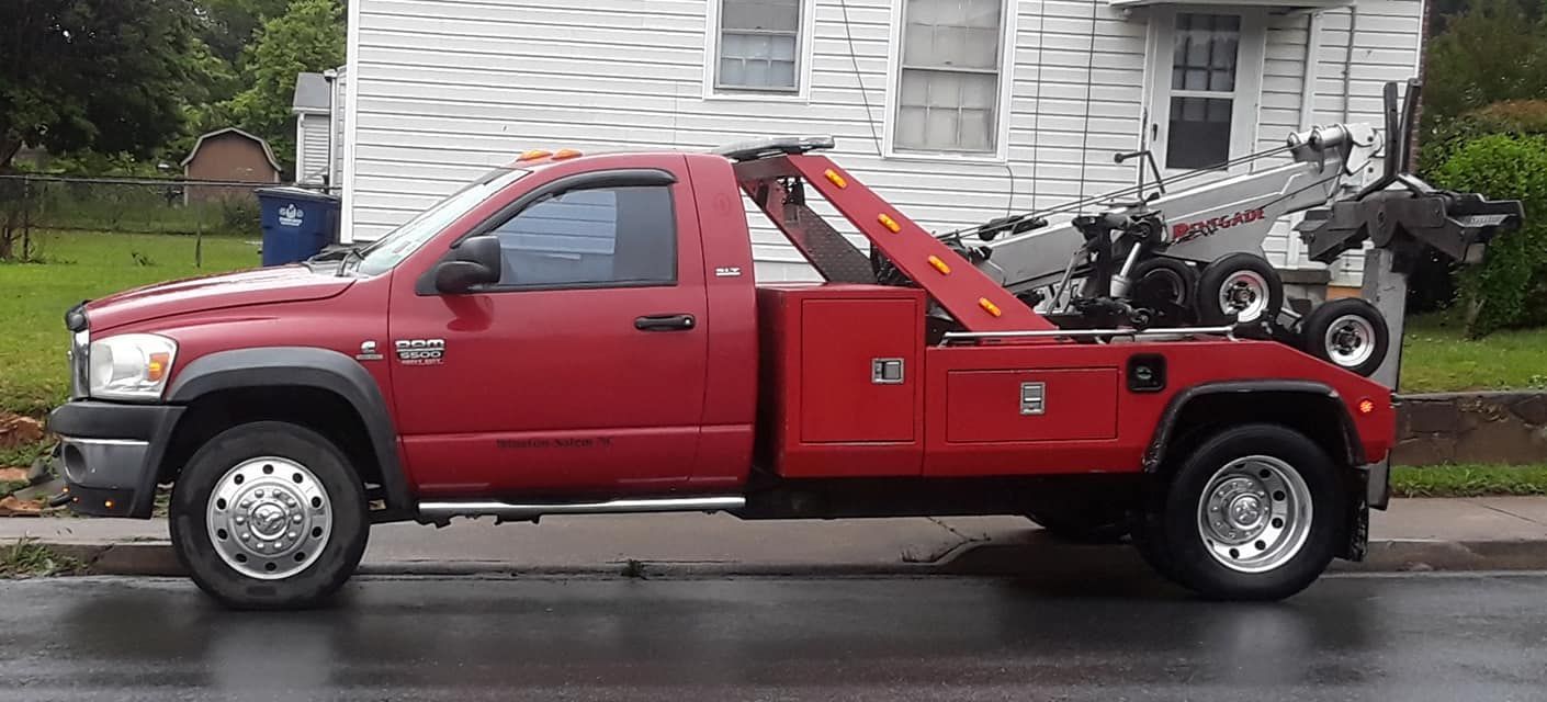 A red tow truck is parked on the side of the road in front of a house.
