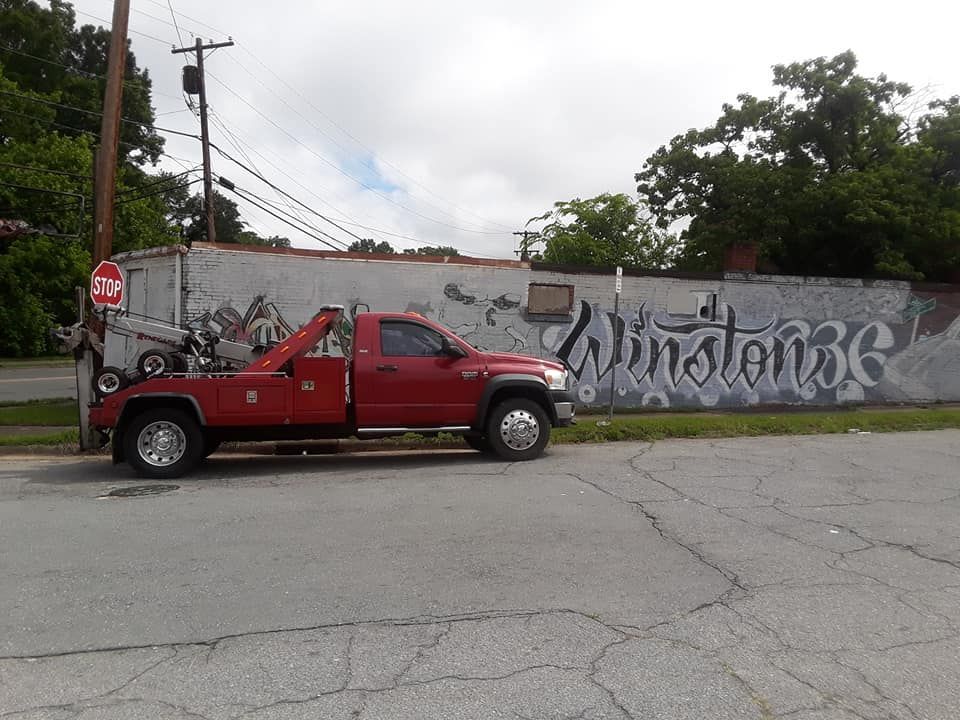 A red tow truck is parked in front of a wall that says winstone